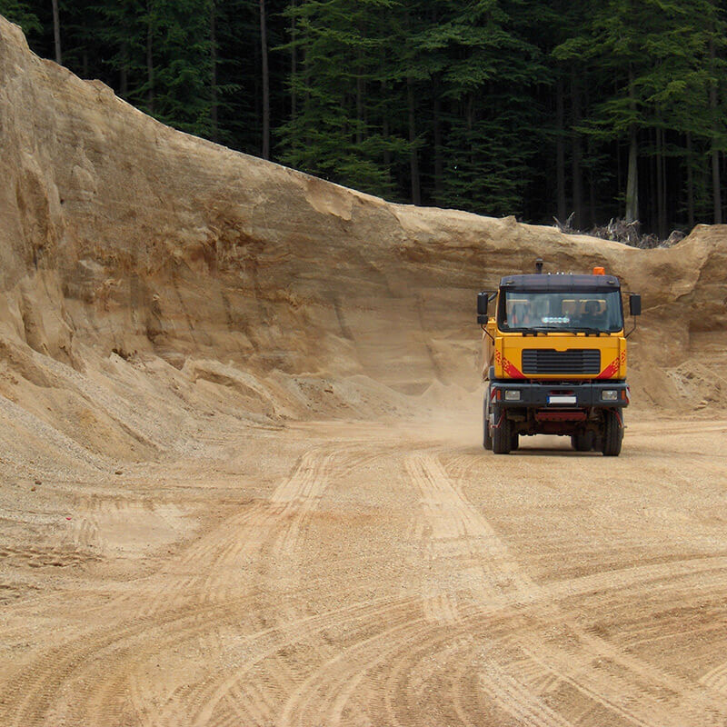 Schulz Landschaftsplanung Lastwagen fährt inmitten einer Kiesgrube, in der Kies abgebaut wird.